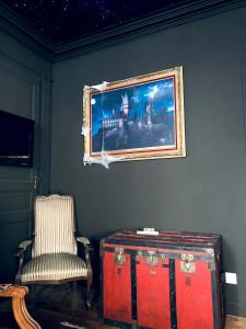 Una habitación con una silla, un cuadro y una maleta roja. en Le refuge des Mans-raudeurs, en Le Mans