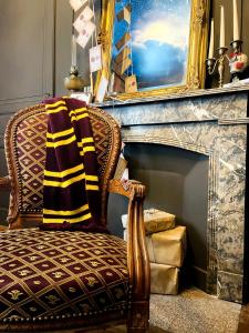 Una silla con una manta junto a una chimenea. en Le refuge des Mans-raudeurs, en Le Mans