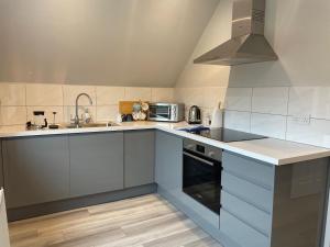 a kitchen with white cabinets and a sink and a stove at The Barn at Hydestile Stud in Milford