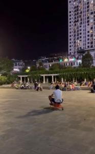 a man sitting in a chair in a plaza at night at Tâm Anh Hotel in Hanoi +6 photos