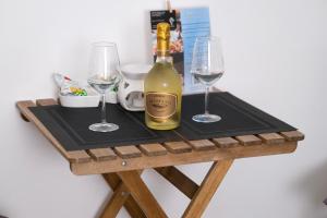 eine Flasche Wein auf einem Holztisch mit zwei Gläsern in der Unterkunft Kosmosuite in Brindisi