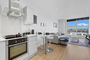 a kitchen with white cabinets and a living room with a couch at Modern 1BR Above Train to Kings Cross in Potters Bar