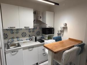 a kitchen with white cabinets and a wooden counter top at Holiday Home - Si Do Relais in Pozzuoli