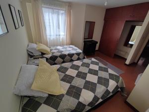 two beds in a hotel room with checkered sheets at Sucre serenity Home in Sucre