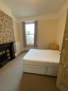 a bedroom with a bed and a fireplace and a window at 6 Bedroom PLYMOUTH in Moffat