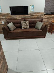 a brown couch with pillows on a white tile floor at Espaço Beatriz in Aparecida