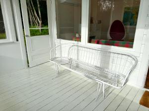 un banc en métal posé sur le porche d'une maison dans l'établissement Lakefront midcentury vintage, à Island Pond