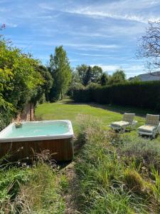 a bath tub in the grass next to two chairs at Grandes Molaises in Les Hogues +8 photos