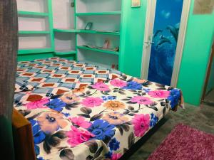 a bed with a floral comforter in a room at Kanchan Lata Homestay in Banāras Cantonment