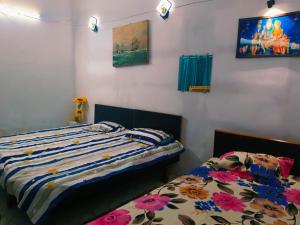 a bedroom with two beds and paintings on the wall at Kanchan Lata Homestay in Banāras Cantonment +25 photos