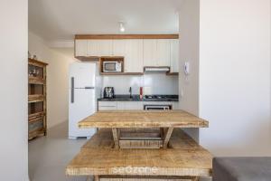 a kitchen with a wooden table and a white refrigerator at Apto c/ Churrasqueira a 750 m da Praia RRV0202 in Gravata