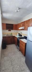 a kitchen with wooden cabinets and a stove and a refrigerator at Amplio apartamento, Excelente ubicación 3 habitaciones 5 camas in Coatzacoalcos