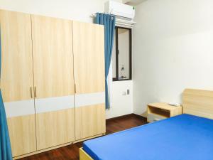a bedroom with wooden cabinets and a blue bed at Cozy 1-Bedroom Apartment at Ehome Ben Luc Waterpoint Block A5 