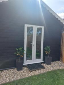 zwei Topfpflanzen vor einem Haus in der Unterkunft The Garden Room at Poplar Cottage in Wick Saint Lawrence