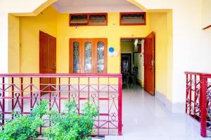a yellow house with red doors and a balcony at Hotel O Modern Home in Guwahati +23 photos