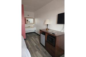 ローズバーグにあるHotel O Motel 10 Lordsburg I-10のテレビが置かれた机があるホテルの部屋
