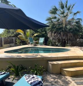 a swimming pool with two chairs and an umbrella at Vila das Águas in Atins