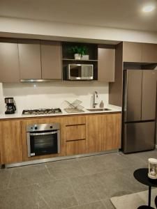 a kitchen with wooden cabinets and a stainless steel refrigerator at Loft Plaza Centro Zapopan in Guadalajara +12 photos