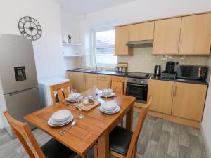 a kitchen with a wooden table with chairs and a refrigerator at Castleview Coastal Comfort in Oystermouth