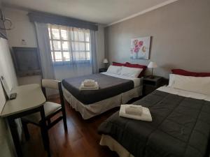 a bedroom with two beds and a table and a chair at Hostal malvinas in Ushuaia