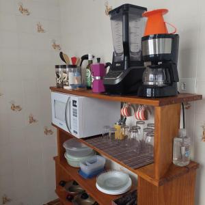 a shelf with a coffee maker and a microwave at Apartamento Brisa Do Mar em Peruíbe in Peruíbe