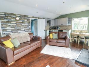 a living room with two leather couches and a kitchen at Harbour Lights in Holyhead