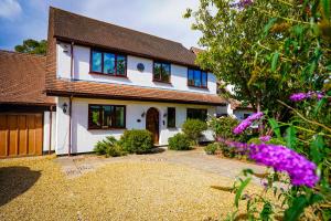 ein weißes Haus mit einem Hof mit lila Blumen in der Unterkunft Bright & Spacious 5-Bedroom Stay near Cambridge in Hardwick