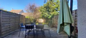 a patio with a table and chairs and an umbrella at Un Havre de Calme - proche Ferme de la Doudou in Cheptainville +14 photos