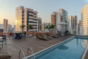 a rooftop deck with a pool and tables and chairs at D8 Hotel in Fortaleza
