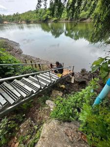 een man die op een brug over een rivier zit bij โฮมสเตย์ติดแม่น้ำปิง in Sam Ngao +1 foto