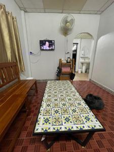 een tafel in een kamer met een bank en een tv bij โฮมสเตย์ติดแม่น้ำปิง in Sam Ngao