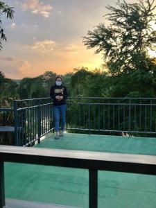 een persoon staat op een brug bij โฮมสเตย์ติดแม่น้ำปิง in Sam Ngao