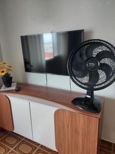 a black fan sitting on top of a tv at Apartamento Brisa Do Mar em Peruíbe in Peruíbe