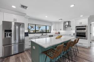 a kitchen with white cabinets and a large island with bar chairs at Club Red in Sanibel