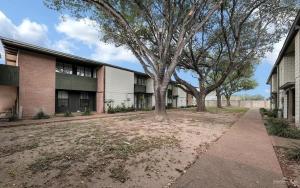 a building with two trees in front of it at Charming 1BR Condo Near UTRGV & Downtown Edinburg in Edinburg