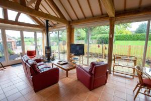 a living room with couches and a tv and windows at Nature's Lodge in Wolverley