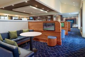 a waiting room with a tv and a table and chairs at Courtyard by Marriott Atlanta Airport South/Sullivan Road in Atlanta