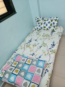 a bed in a room with a bedspread and pillows at Near Swargate Vrundavan 2 BHK bungalow in Pune