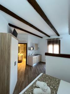 cocina y sala de estar con paredes blancas y suelo de madera en Apartamentos Los Belloso, en Alange