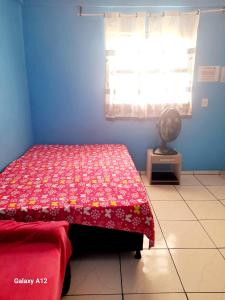 a bedroom with a bed with a red bedspread at kitnet Conjugado em Tramandai in Tramandaí