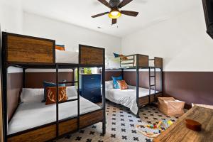 two bunk beds in a room with a ceiling fan at New The Chaletresorthot Tubgameroomfirepit in Massanutten