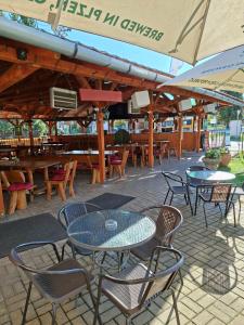 Un patio al aire libre con mesas, sillas y sombrillas. en Grill Terasz Étterem és Szálláshely, en Mezőkövesd