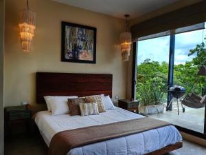 une chambre avec un grand lit et une grande fenêtre dans l'établissement Boho Chic Loft- Stunning Terrace in Central Tulum, à Tulum