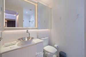 een witte badkamer met een wastafel en een toilet bij Studio c/ churrasq. a 750m da UFSC - PST1409 in Florianópolis +7 foto's