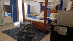 モンバサにあるAffordable neat studio furnished apartment in Mtwapaのベッドルーム(天蓋付きベッド、オットマン付) +2枚の写真