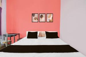 a bedroom with a white bed and a red wall at Hotel O Happy Inn in Gorakhpur