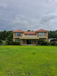 ein großes Haus mit einem großen Grasfeld in der Unterkunft Kalhaar Blues And Greens Premium Villa in Ahmedabad