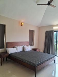 ein Schlafzimmer mit einem großen Bett und einem Deckenventilator in der Unterkunft Kalhaar Blues And Greens Premium Villa in Ahmedabad
