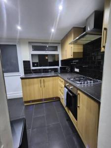 Una cocina con gabinetes de madera y un horno de estufa. en Comfy 3-Bed House - Sleeps 6 & Free Parking, en Tilbury