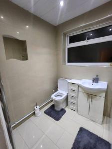 Un baño con inodoro, lavabo y ventana. en Comfy 3-Bed House - Sleeps 6 & Free Parking, en Tilbury